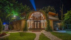 A modern hotel with a glass facade, a spiral staircase, and a stone pathway leading to the entrance. - Hotel Legjenda (Shkodër)