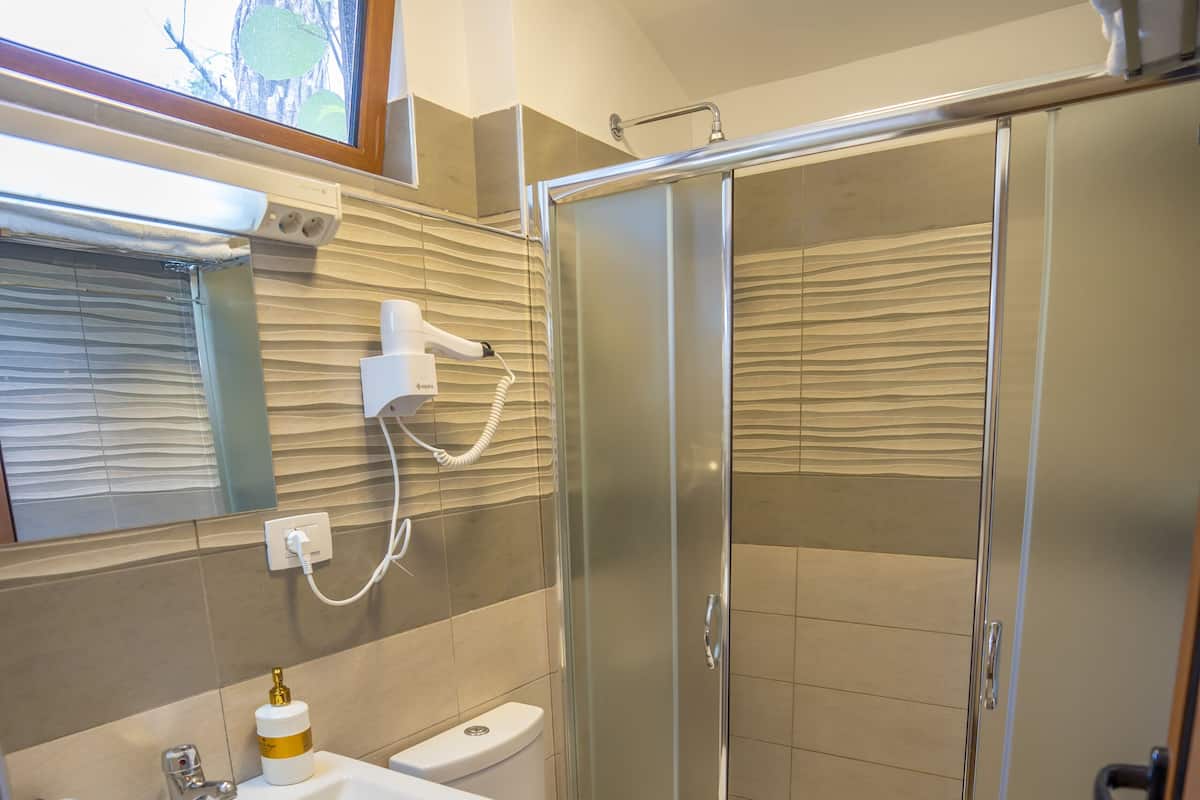 Un baño con lavamanos, inodoro y cabina de ducha de vidrio.