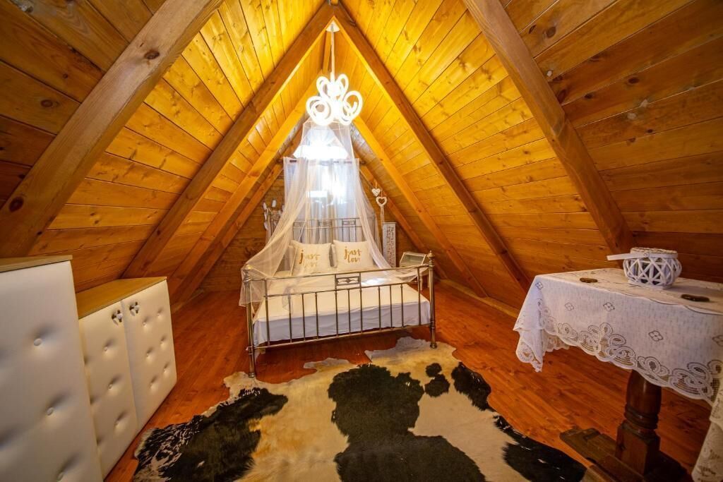 A cozy attic bedroom with a canopy bed, a small table with a lace tablecloth, and a cowhide rug.
