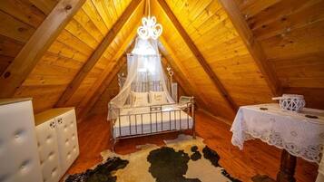 Um quarto de sótão acolhedor com cama de dossel, uma mesa pequena com toalha de renda e um tapete de couro bovino.