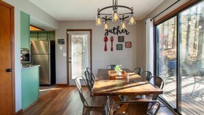 Un comedor con una mesa y sillas de madera, un candelabro y vistas al exterior a través de amplios ventanales.