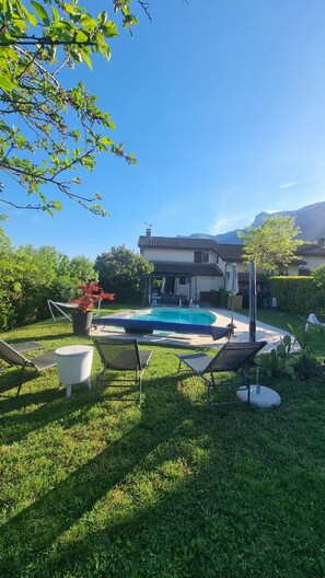Una casa con piscina, muebles de jardín y un jardín.