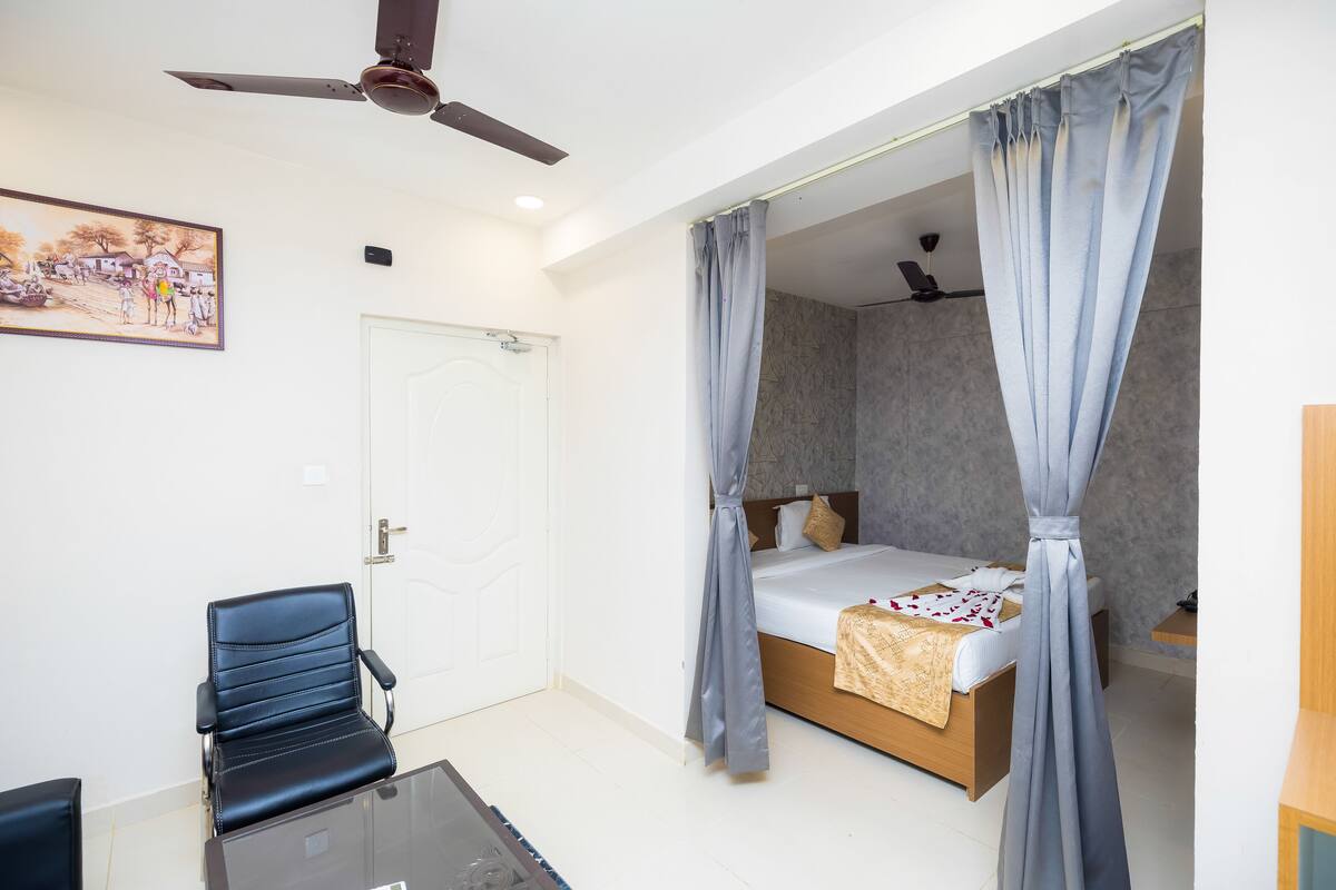 Ein Schlafzimmer mit einem Bett, einem Sessel, einem Deckenventilator und einer Tür.