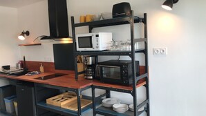 A compact kitchen with a microwave, toaster, and a coffee machine on a black metal shelf. - Studio 35 m2 Refait à Neuf (Fougères)