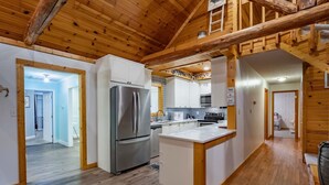 A modern kitchen with wooden beams, a stainless steel refrigerator, and a central island.