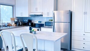 Una cocina moderna con armarios blancos, una isla central y electrodomésticos de acero inoxidable.