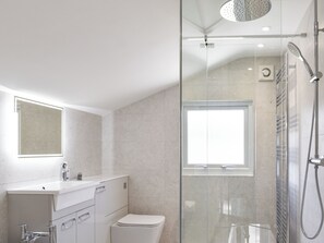 A modern bathroom with a glass shower enclosure, a white sink, and a toilet.