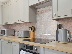 A modern kitchen with white cabinets, a microwave, a toaster, a kettle, and a coffee maker.
