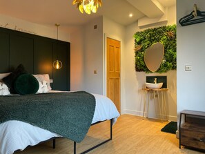 A modern bedroom with a bed, bedside lamp, and a wall-mounted mirror. - Looking for a romantic escape in the countryside, with outdoor bathtub ! (Ashford)