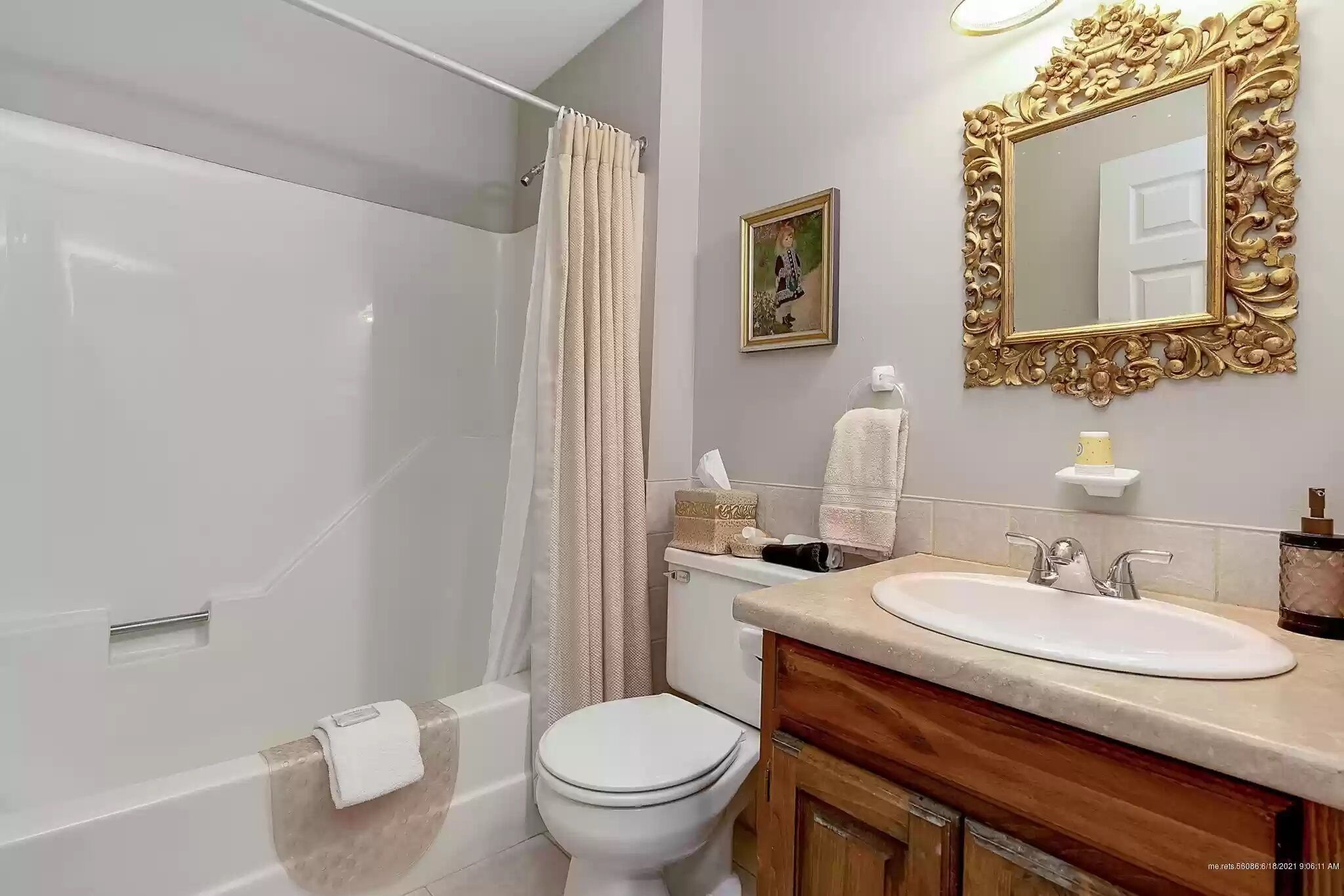 Ein Badezimmer mit Badewanne, Toilette, Waschbecken und einem großen, verzierten Spiegel.