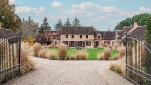 A large, multi-story building with a gravel driveway leading to a gated entrance.