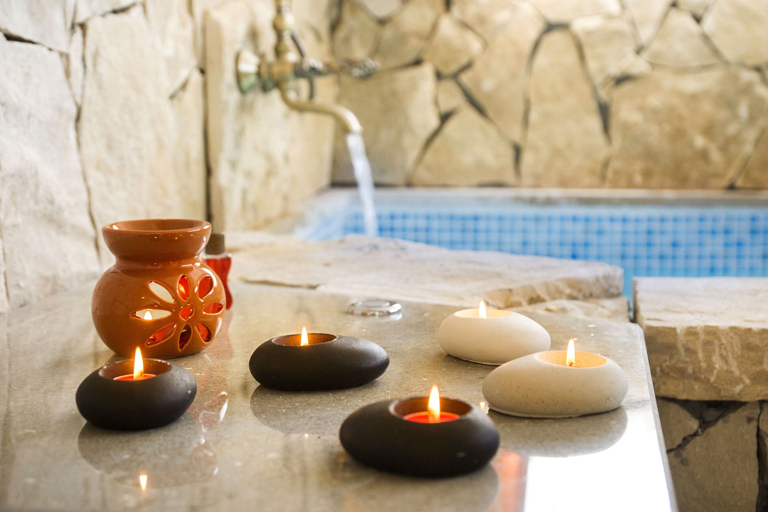 A stone-tiled area with candles and a decorative pot.