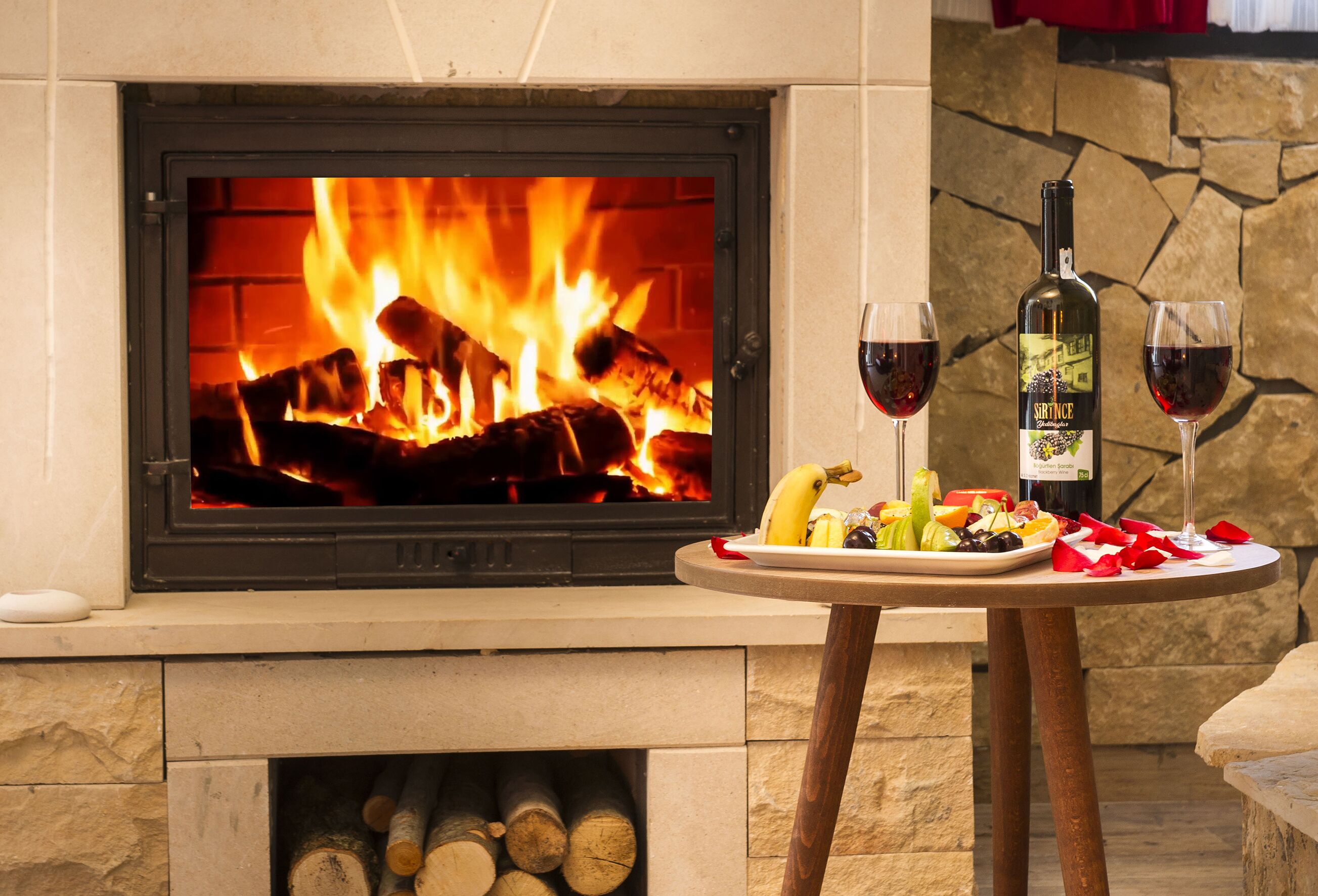 Una chimenea encendida, una mesa con una botella de vino, copas y fruta.