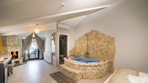 A modern bedroom with a stone wall, a hot tub, and a wooden floor.