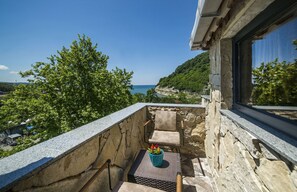 A balcony with a stone wall, a chair, and a potted plant. - Nostalji Butik Otel (Sile)