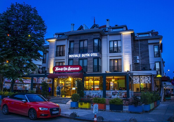 Un hotel con un cartel que dice "Nostalji Butik Hotel" y un restaurante llamado "Nostalji Cafe Restaurant" en primer plano.