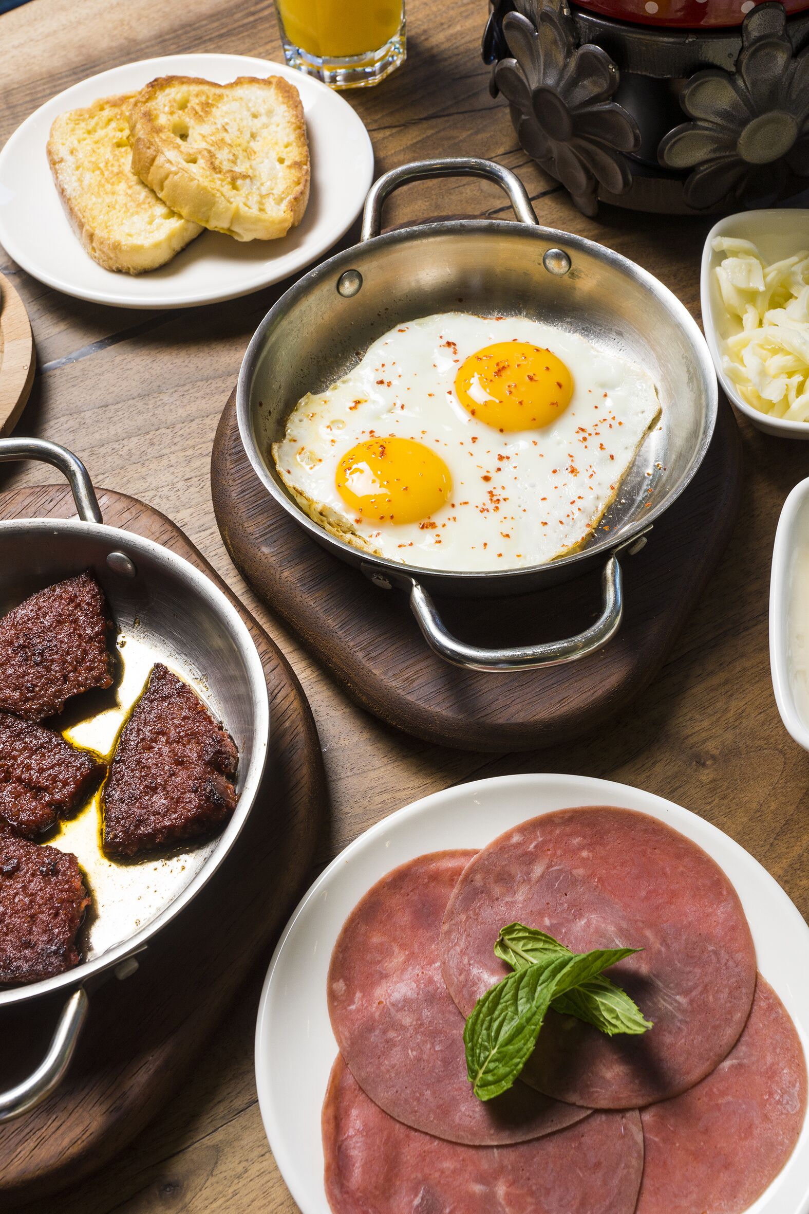 A breakfast setting with eggs, toast, and meat dishes.