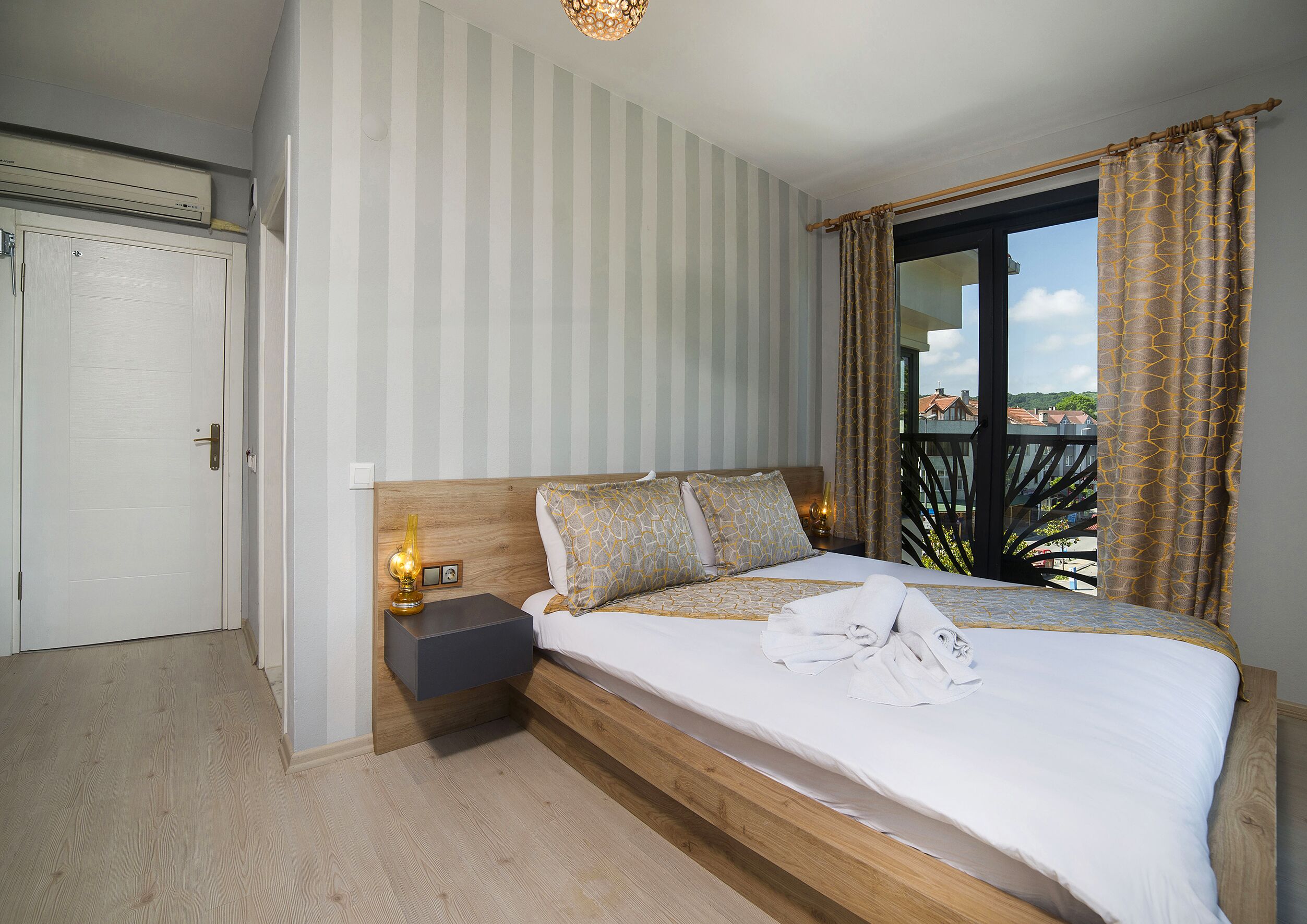 A bedroom with a bed, bedside table, and a view of the outside.