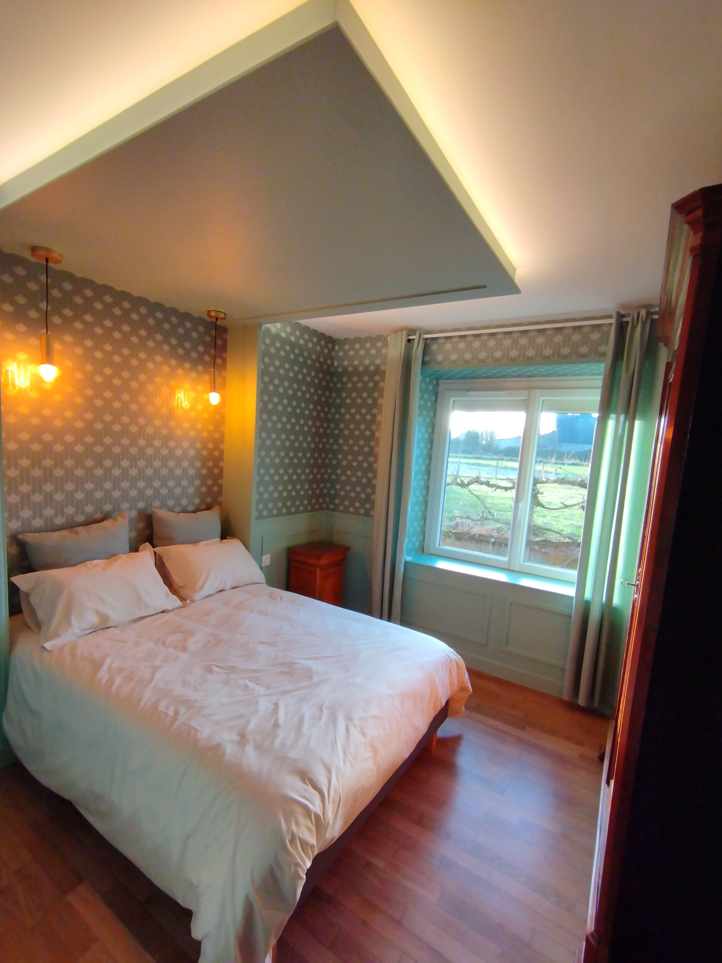 Una camera da letto con un letto grande, due lampade sui comodini, una finestra con tende e un comodino in legno.