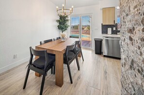 Un comedor con mesa y sillas de madera, una araña y vista a una piscina a través de puertas de vidrio.
