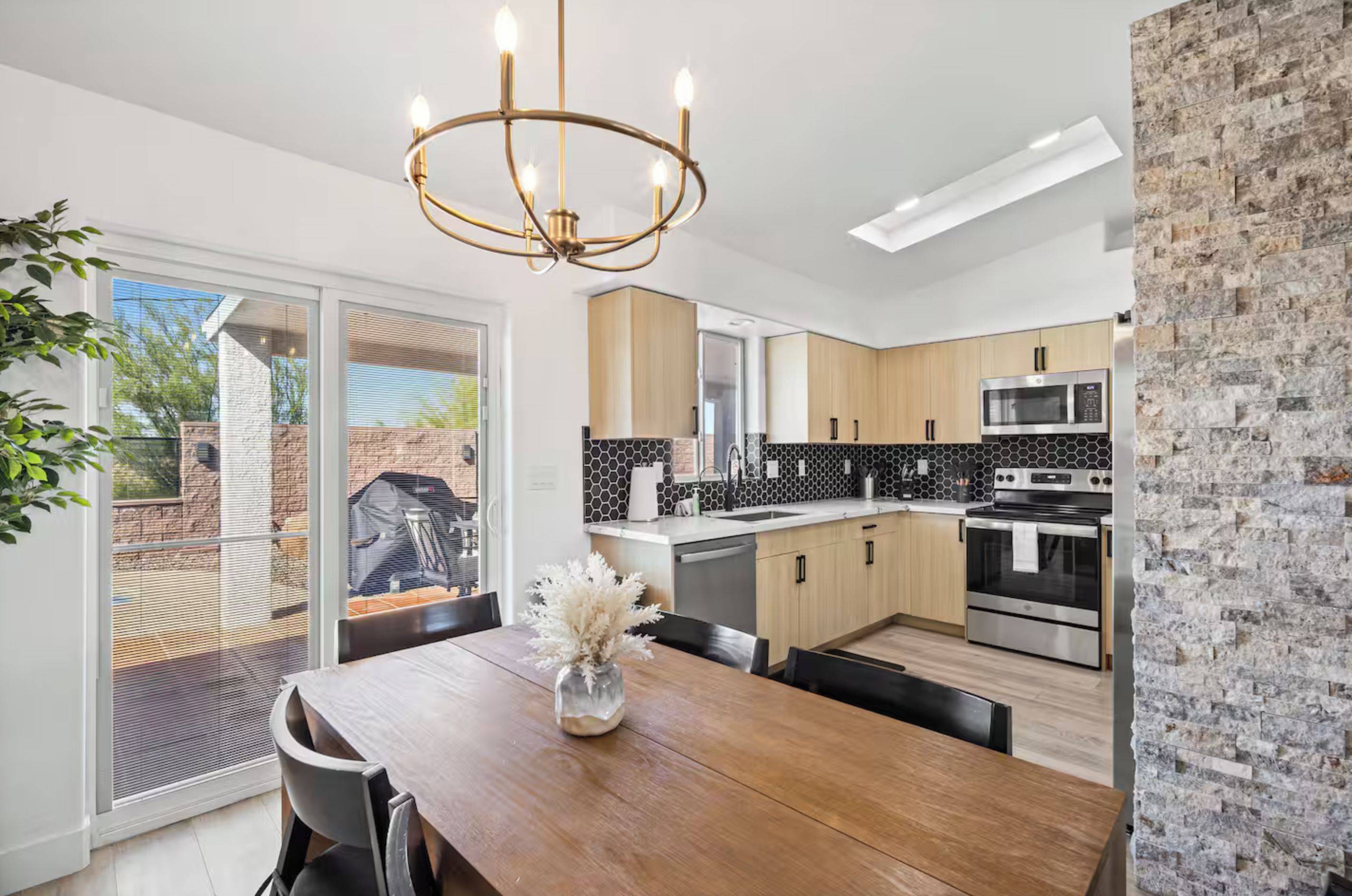 Een moderne keuken met een inbouwoven, magnetron en een eethoek met een houten tafel en stoelen.