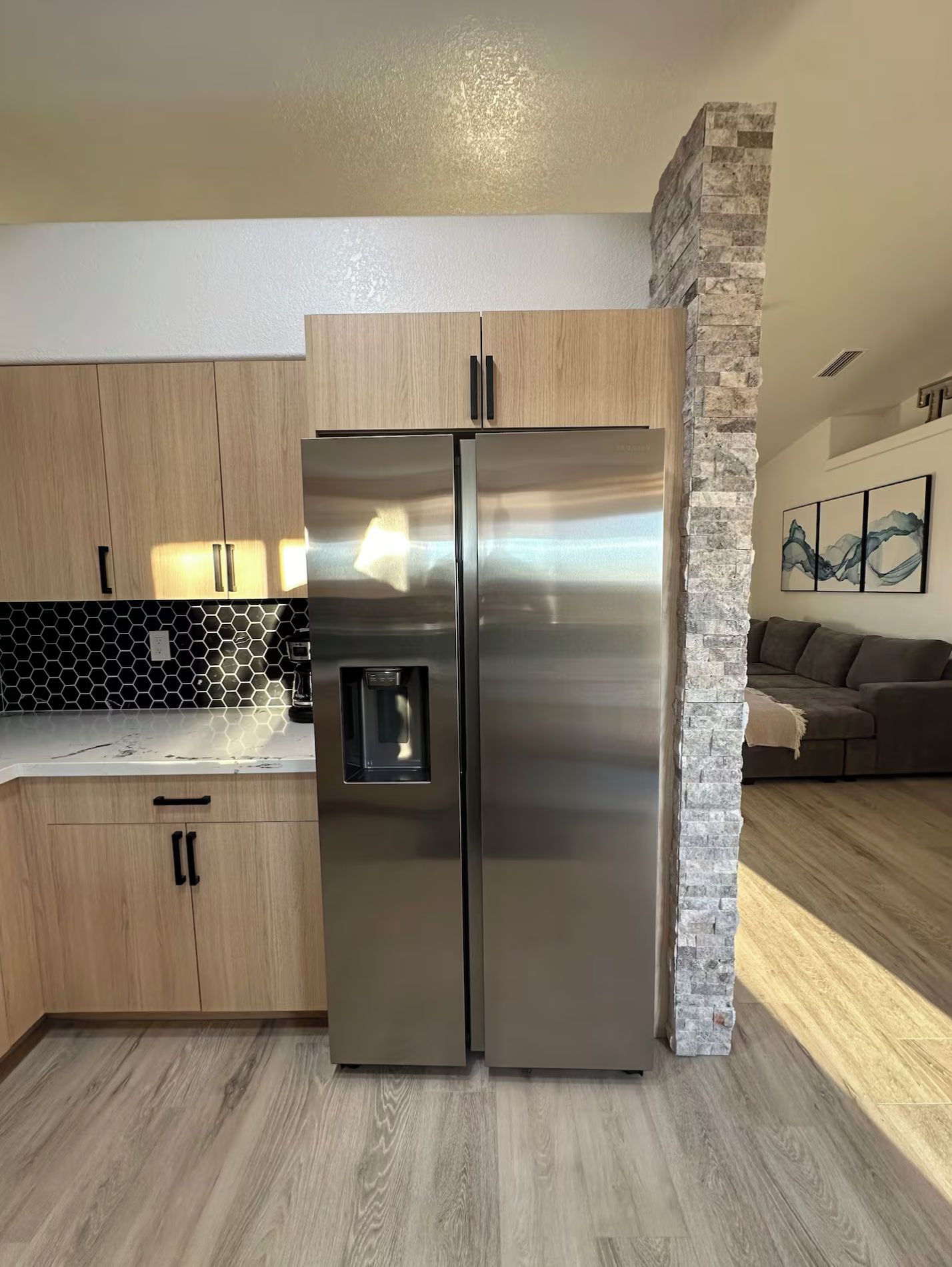 Eine Küche mit einem Edelstahl-Kühlschrank, Holzschränken und einer Wand mit Steinverkleidung.