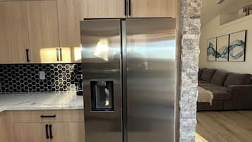 Eine Küche mit einem Edelstahl-Kühlschrank, Holzschränken und einer Wand mit Steinverkleidung.