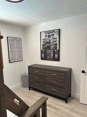 Una habitación con un aparador de madera oscura, un cuadro colgado en la pared de equipo de audio y una obra de arte con un diseño geométrico.