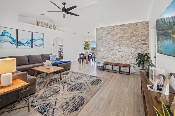 Una sala moderna con un sofá, una mesa de centro y una zona de comedor con sillas y un banco.