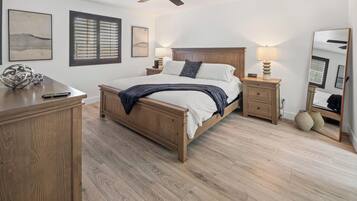 Ein Schlafzimmer mit einem hölzernen Bett, Nachttischen, einem Deckenventilator und Bildern an den Wänden.