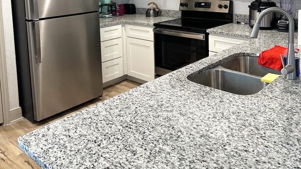 A modern kitchen with white cabinets, stainless steel appliances, granite countertops, and a built-in microwave. - SeaWorld & Lackland Air Force Base Modern Home (San Antonio)