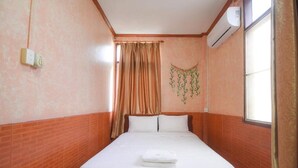 A hotel room with a single bed, a window with curtains, an air conditioning unit, and a wall-mounted light switch. - Intouch vientiane (Vientiane)