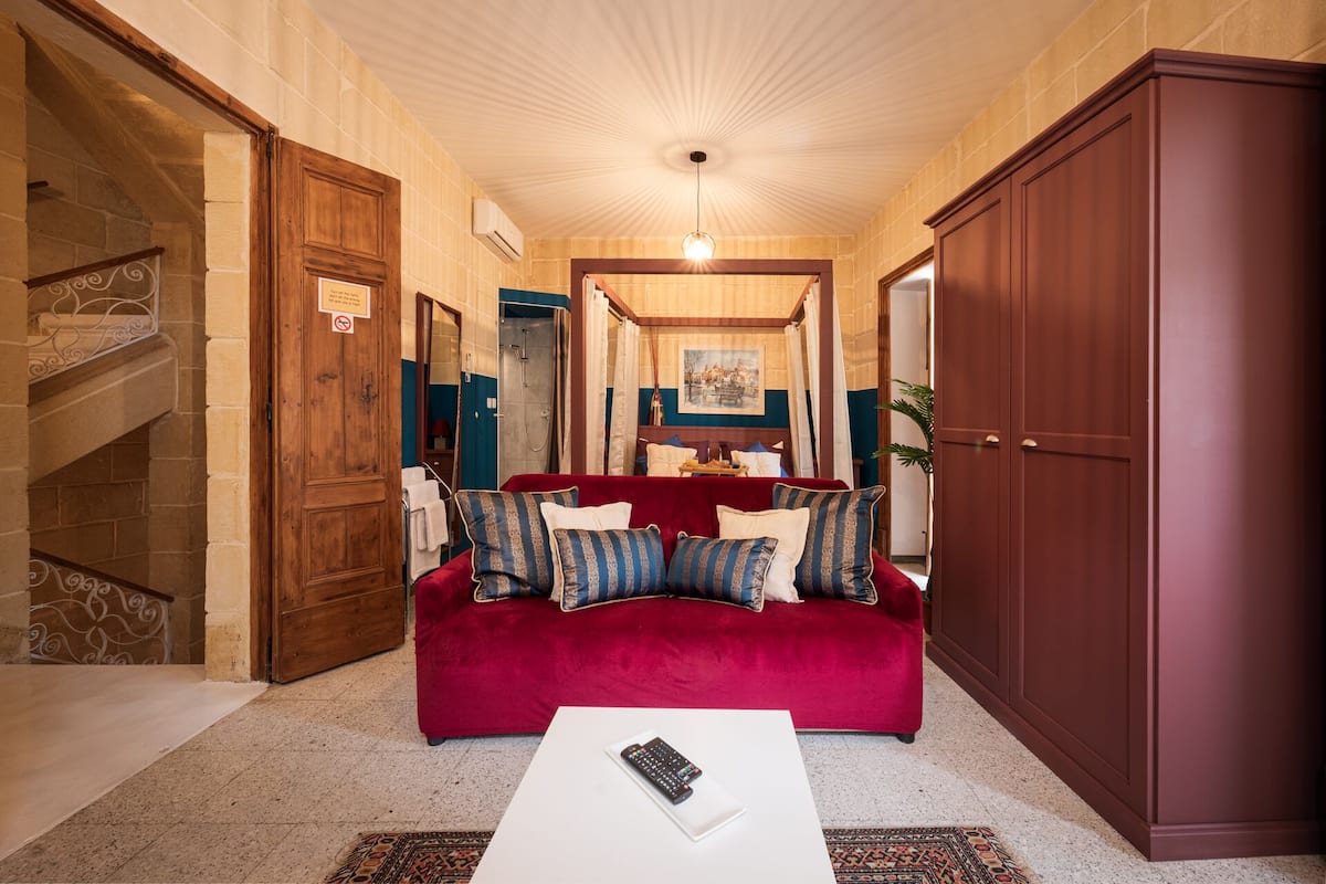 A hallway with a red sofa, a white coffee table, and a large wooden wardrobe.