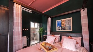 A bedroom with a bed, a bedside table with a tray of breakfast, a shower, and a painting on the wall. - Concetta Studio Apartments  (Cospicua)