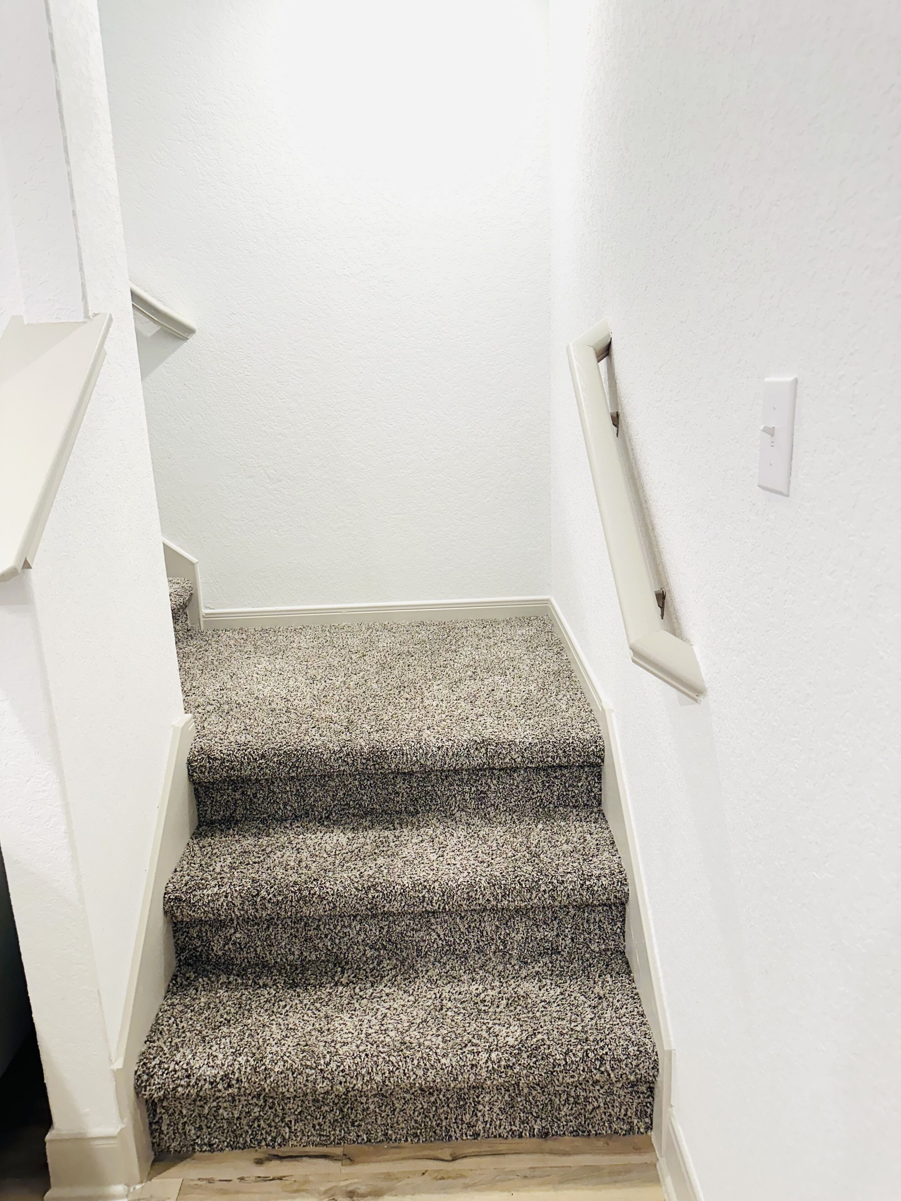 A staircase with carpeted steps leading to a landing.