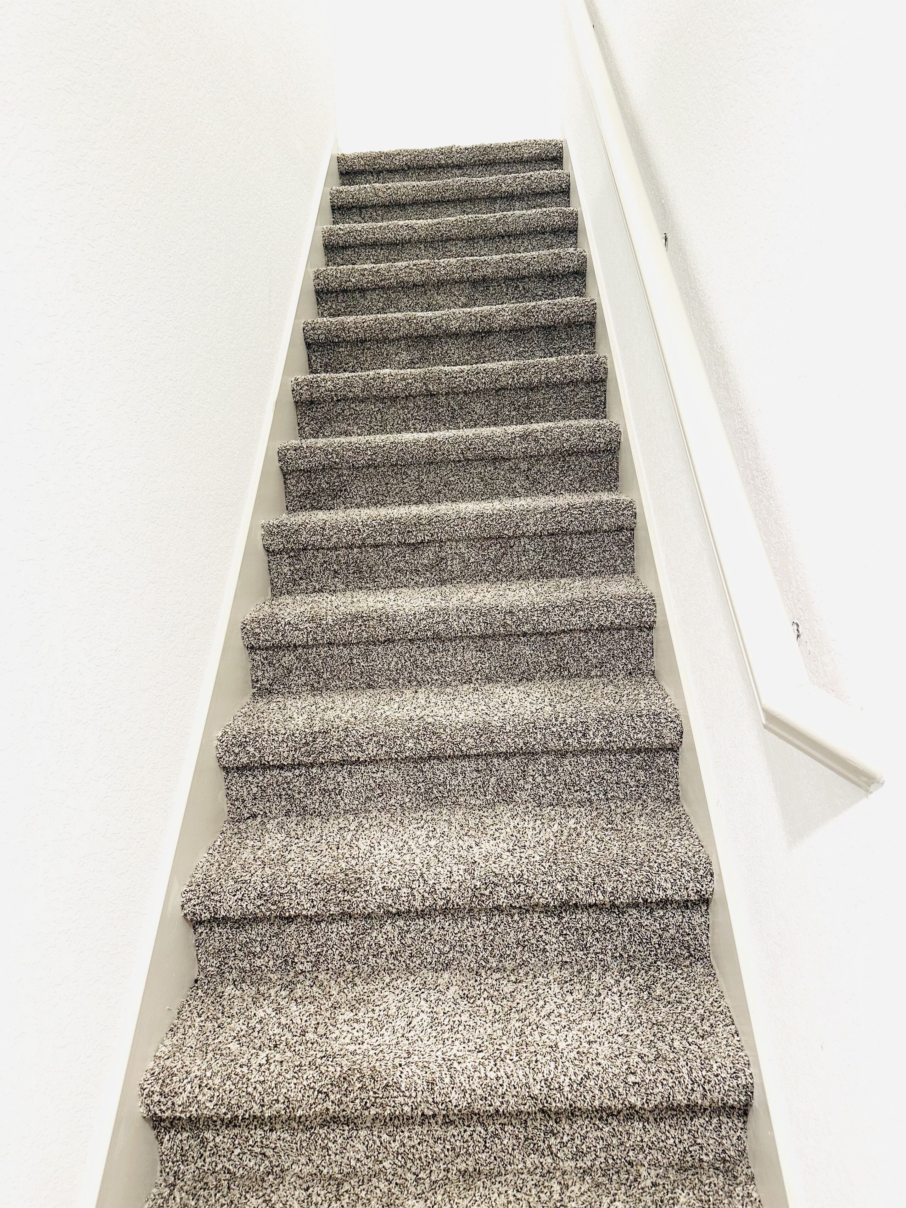 A staircase with a textured carpet.