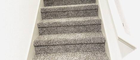 A staircase with a textured carpet.