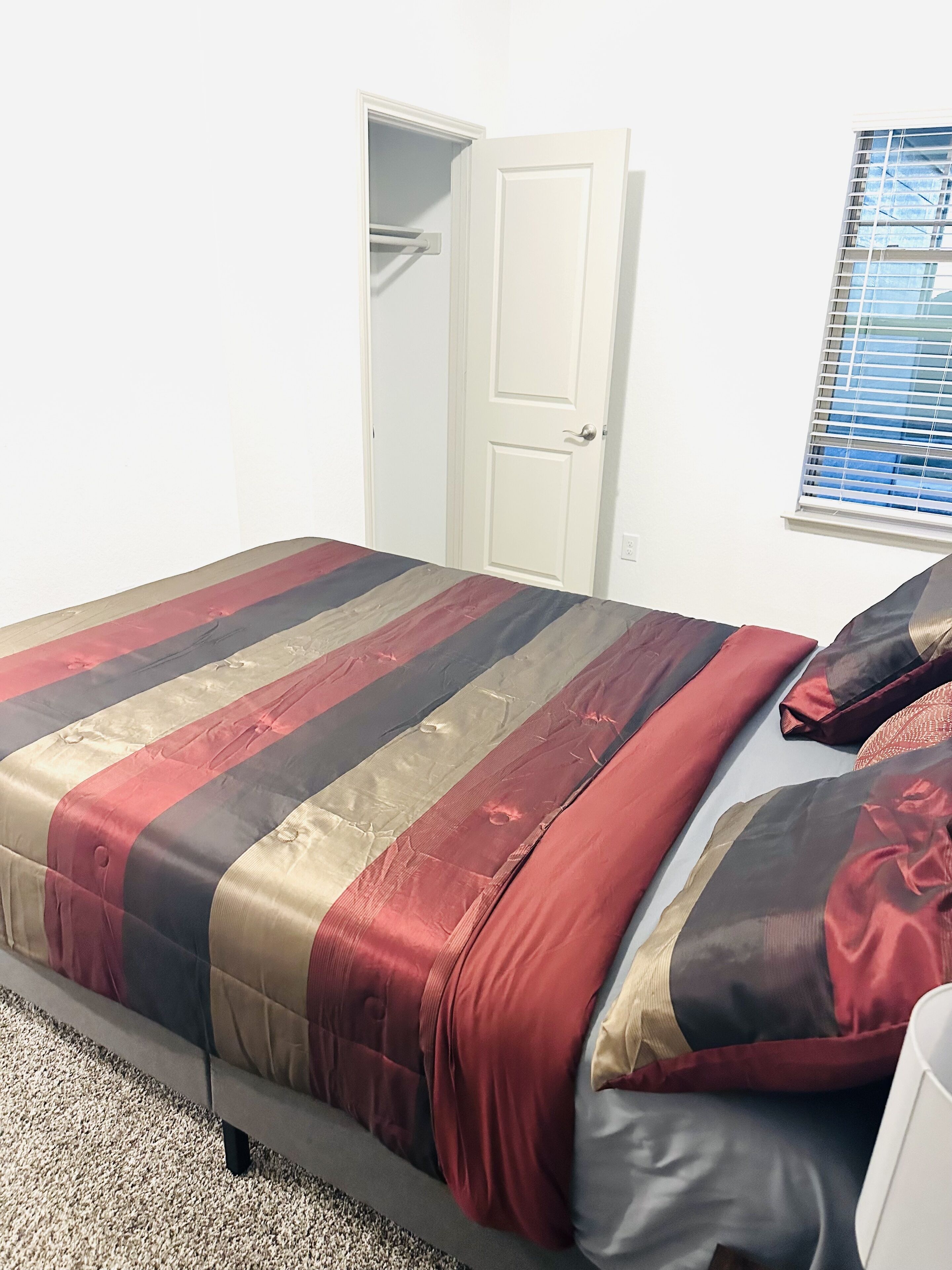 Un dormitorio con cama, armario y ventana con persianas.