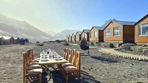 A dining area with a long table set for guests, surrounded by wooden chairs. - Hotel Spiti Villa Himalayan Brothers (Spiti)