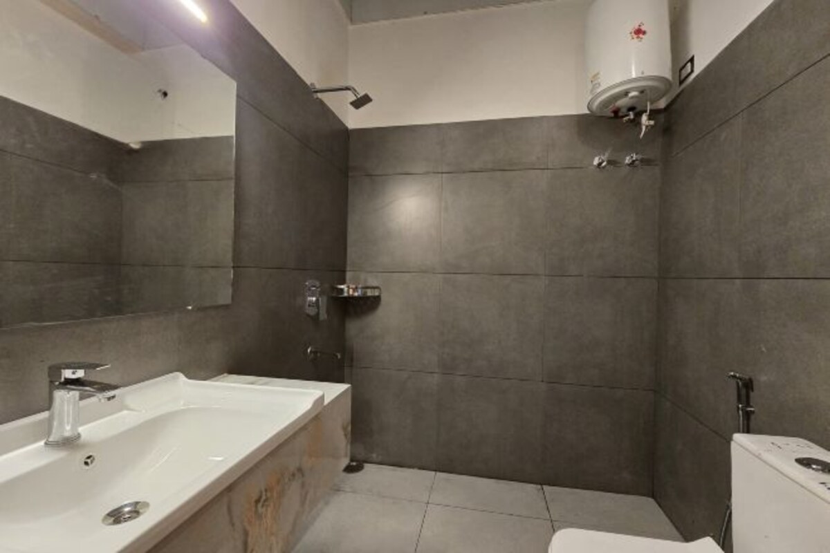 A modern bathroom with a bathtub, toilet, and a large mirror.