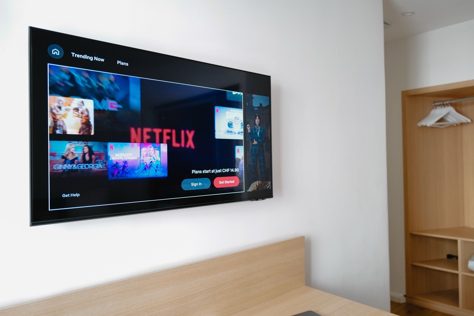 A flat-screen TV mounted on a wall displaying a streaming service interface with options to sign in or get started.