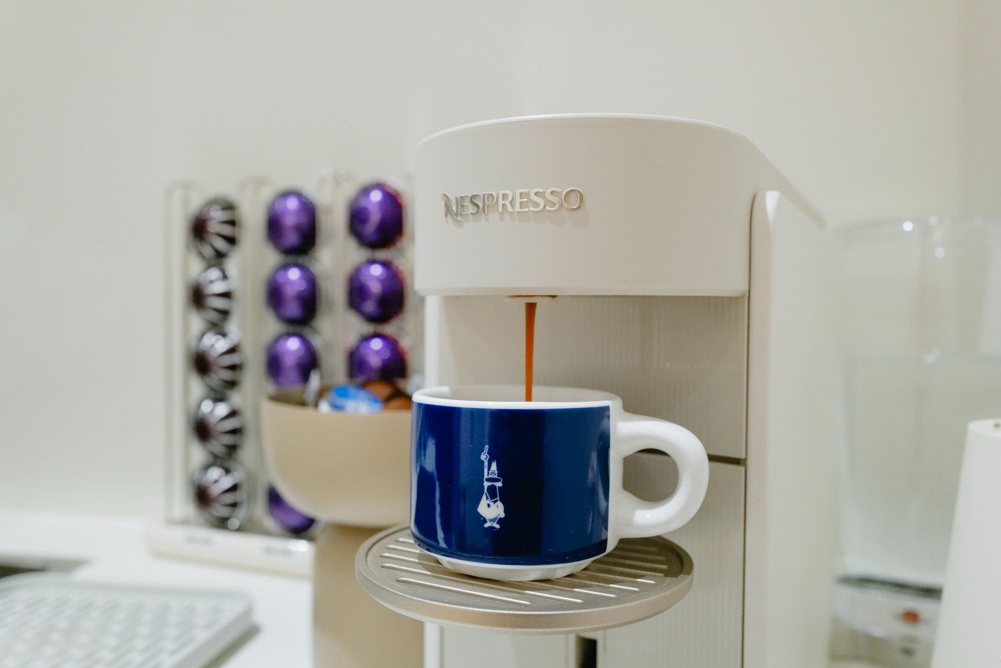 Una máquina de café Nespresso sirviendo café en una taza azul.