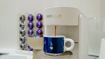 Una máquina de café Nespresso sirviendo café en una taza azul.