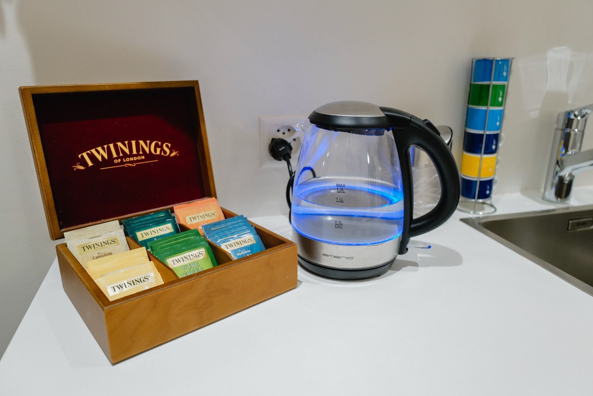 A coffee maker with a water reservoir and a box of Twinings tea bags.