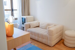 A cozy room with a sofa, a small table, a lamp, and a television. - Rhodania Boutique Hôtel (Geneva)