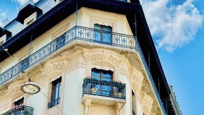 Un immeuble d’angle doté de détails architecturaux raffinés, notamment un balcon orné de balustrades en fer forgé et de jardinières.