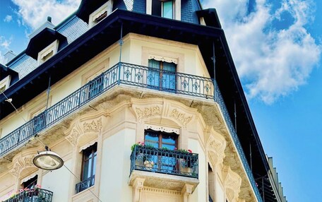 A corner building with ornate architectural details, including a balcony with wrought iron railings and flower boxes.