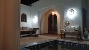 Una habitación con piscina, dos sofás, una lámpara y una puerta.
