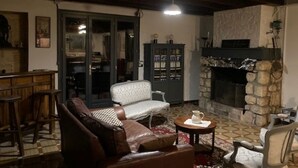 A cozy living room with a fireplace, leather sofa, and a bookshelf. - Maison au Milieu des Vignes Proche de Saint Emilion (Mérignas)