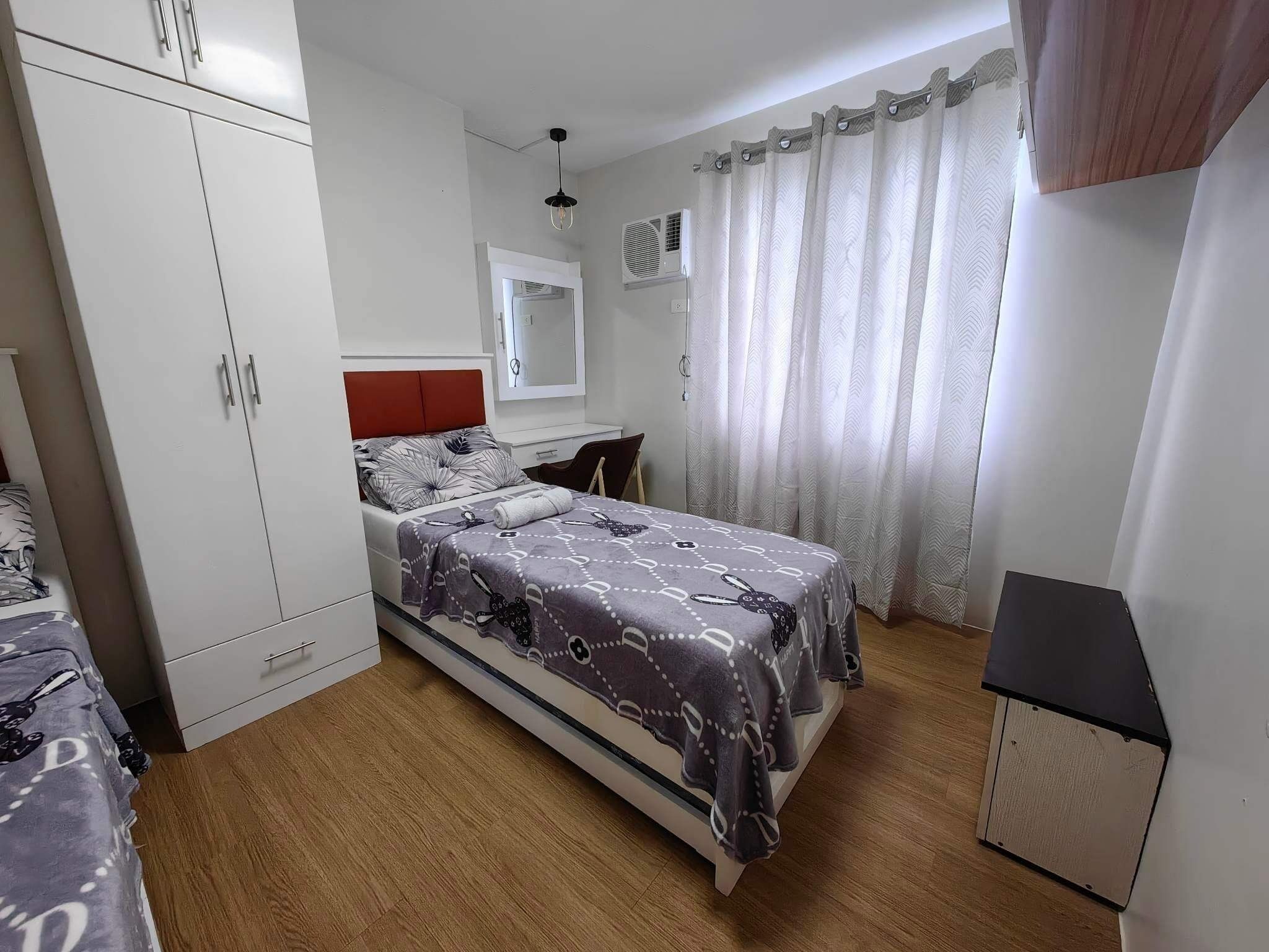 Un dormitorio con cama, armario y un pequeño escritorio.